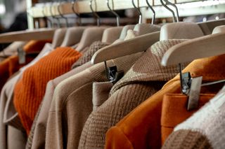 A selection of orange and brown clothing on a rail.