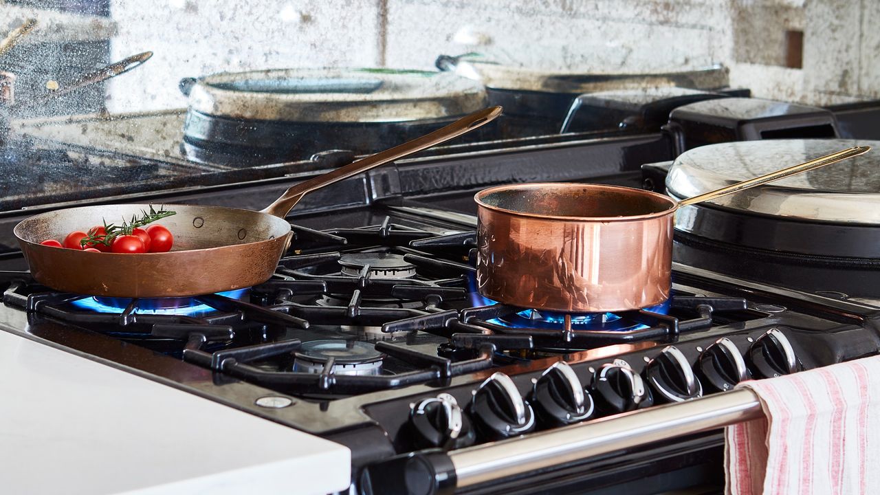 A turned-on gas stove with copper pots on top