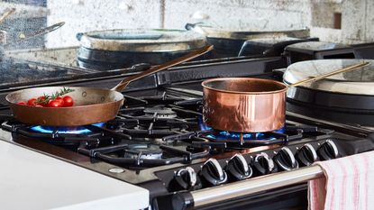 A white kitchen with hanging copper pots