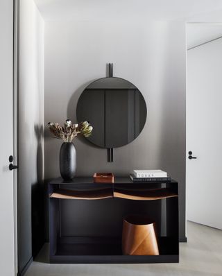 A New York pied-à-terre with gray walls and a sleek black framed mirror