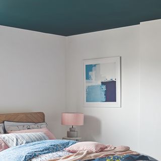 Bedroom with blue and pink bedding, grey walls, navy wall art and navy blue ceiling