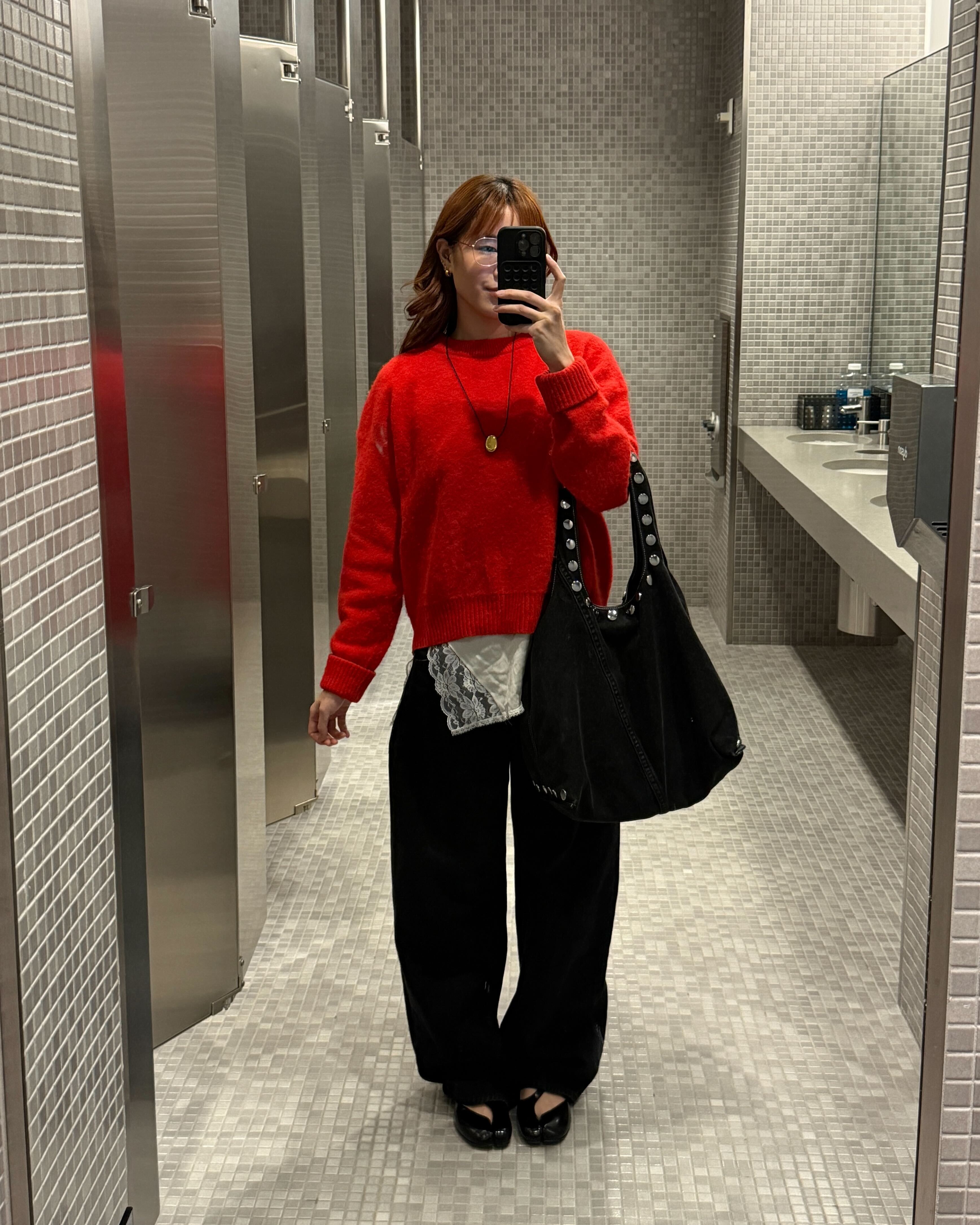 Kristina Ang at the office at her tech job wearing a red sweater, black pants, and black flats.