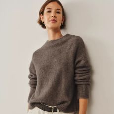 Woman wears taupe alpaca-blend sweater and white jeans