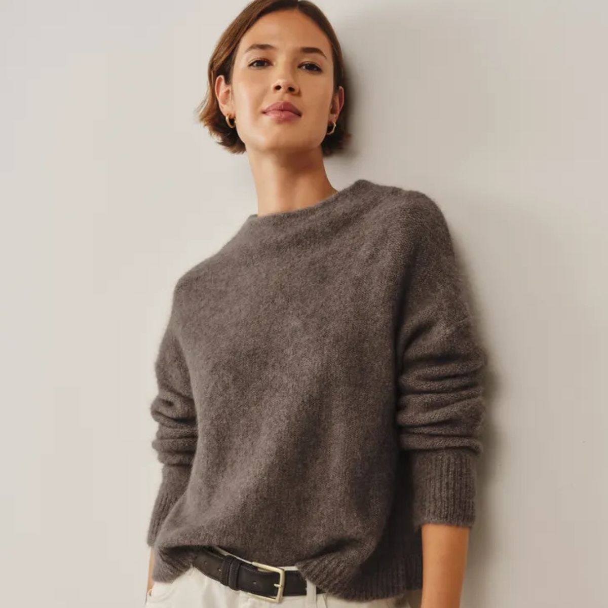 Woman wears taupe alpaca-blend sweater and white jeans