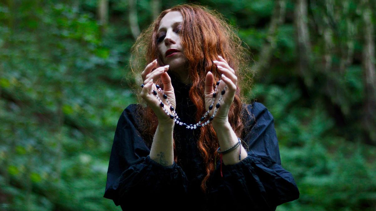 Darkher in a forest holding a rosary