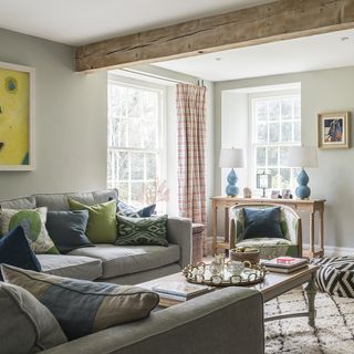 living area with white wall and grey sofa with cushions and arm chair