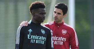 Arsenal manager Mikel Arteta talks to Bukayo Saka during a training session at London Colney on April 30, 2022 in St Albans, England.