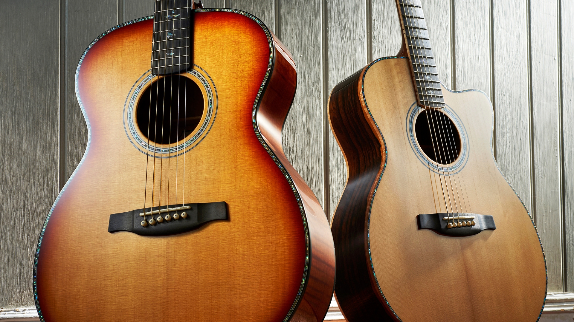 Two acoustic electric guitars leaning against a wall