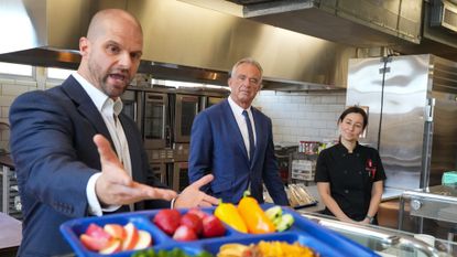HHS Secretary Robert F. Kennedy Jr. (C) listens to a presentation about healthy school lunches. 