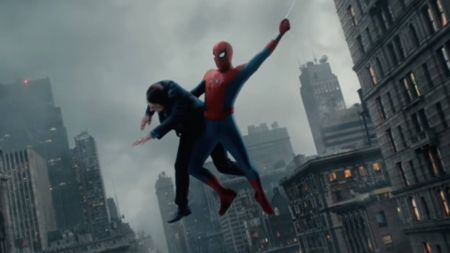 A screenshot from a Spider-Man: Brand New Day trailer clip featuring Spider-Man web-swinging while holding a man