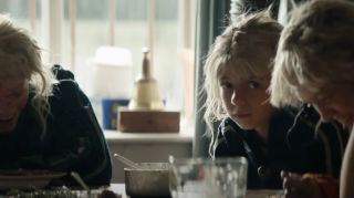 Spike sitting at table with Jimmy Cult members in 28 Years Later: The Bone Temple