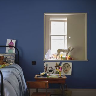 bedroom with blue wall and wooden table and chair