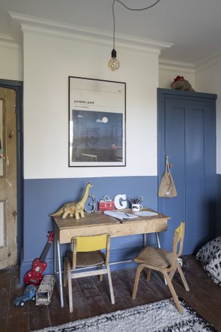Boy's room with painted blue wall and wardribe and vintage wooden desk and chairs