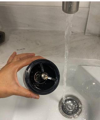 Christina Chrysostomou cleaning burr grinder under running tap in sink (Future Plc test kitchen)