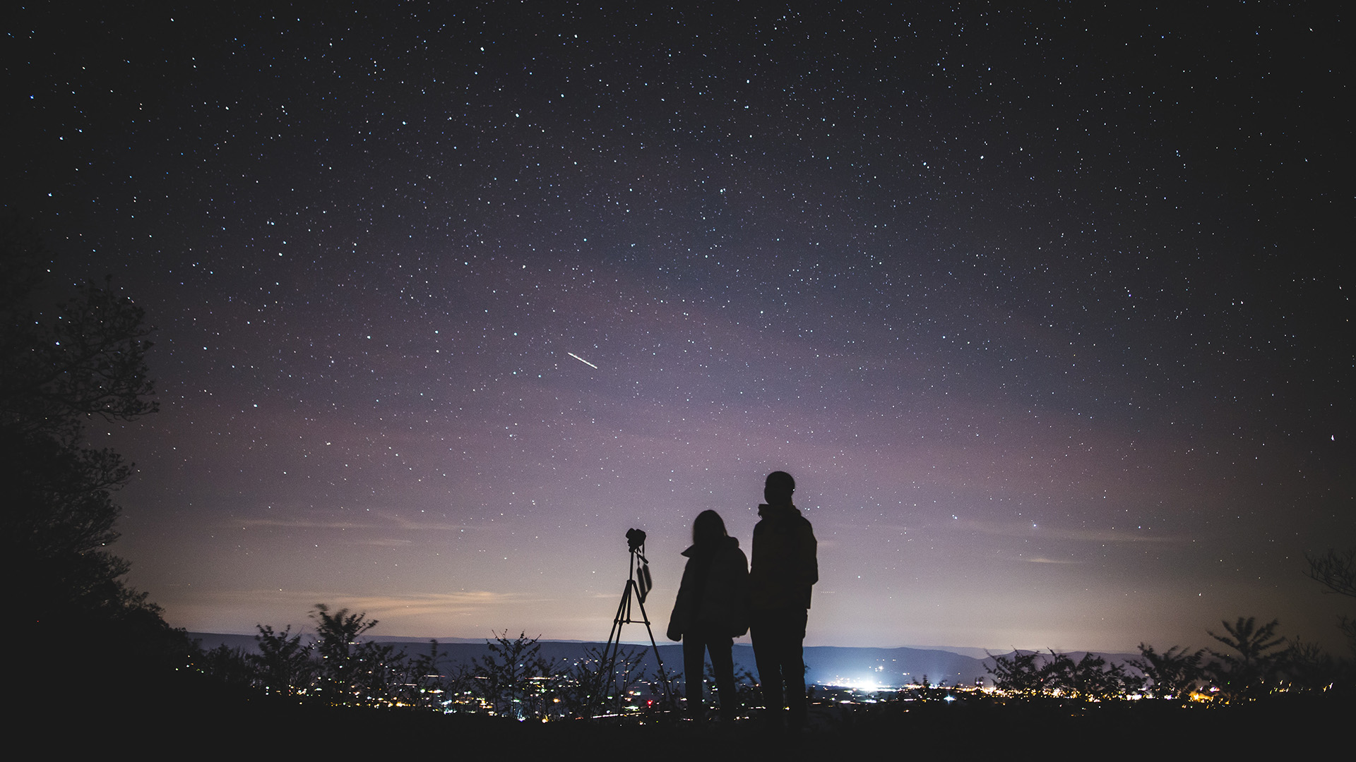 Two people and a camera under a starry sky