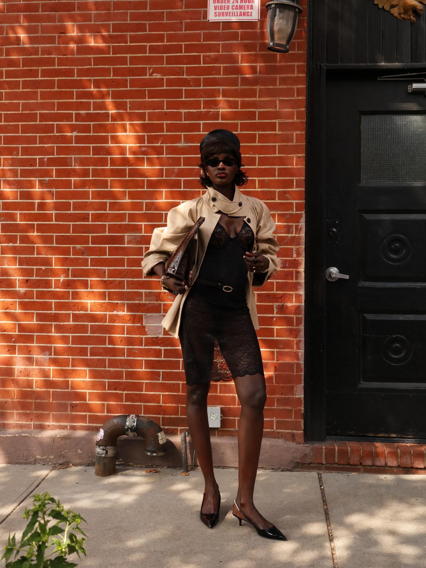 A woman wearing a black lace dress and short trench coat with a mullet bob hairstyle standing on the street in New York