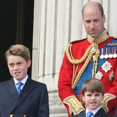 Kate Middleton wears a white dress with navy accents and a matching hat as she joins her husband, Prince William, on the Buckingham Palace balcony