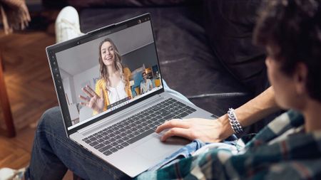 Lenovo 16" IdeaPad Laptop on a man's lap and displaying a video call. 