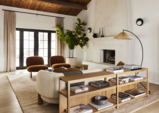 neutral living room with a white sofa, two orche velvet accent chairs, a large green plant in the corner, and a media table on the backside of the sofa