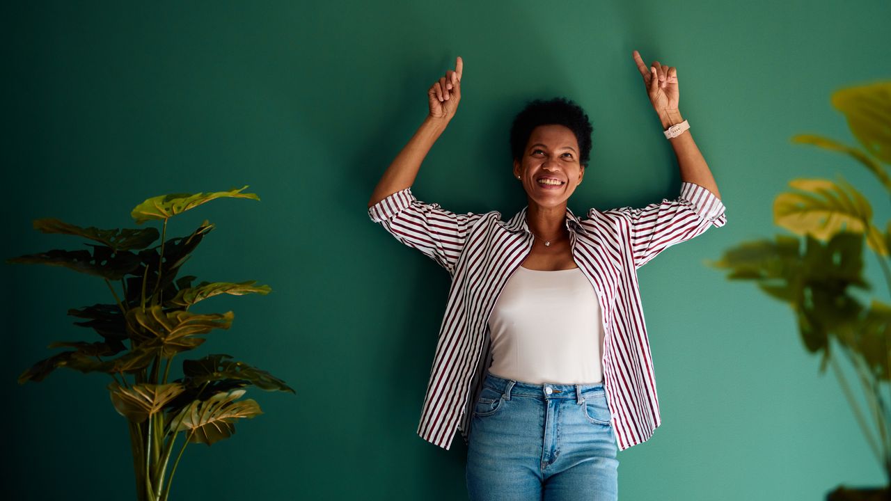 Woman with her back against a wall and arms raised