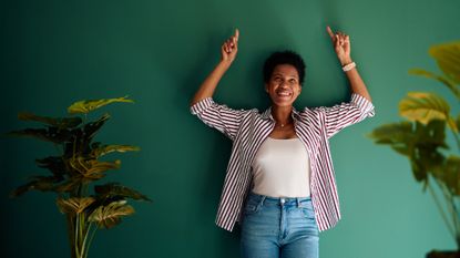 Woman with her back against a wall and arms raised