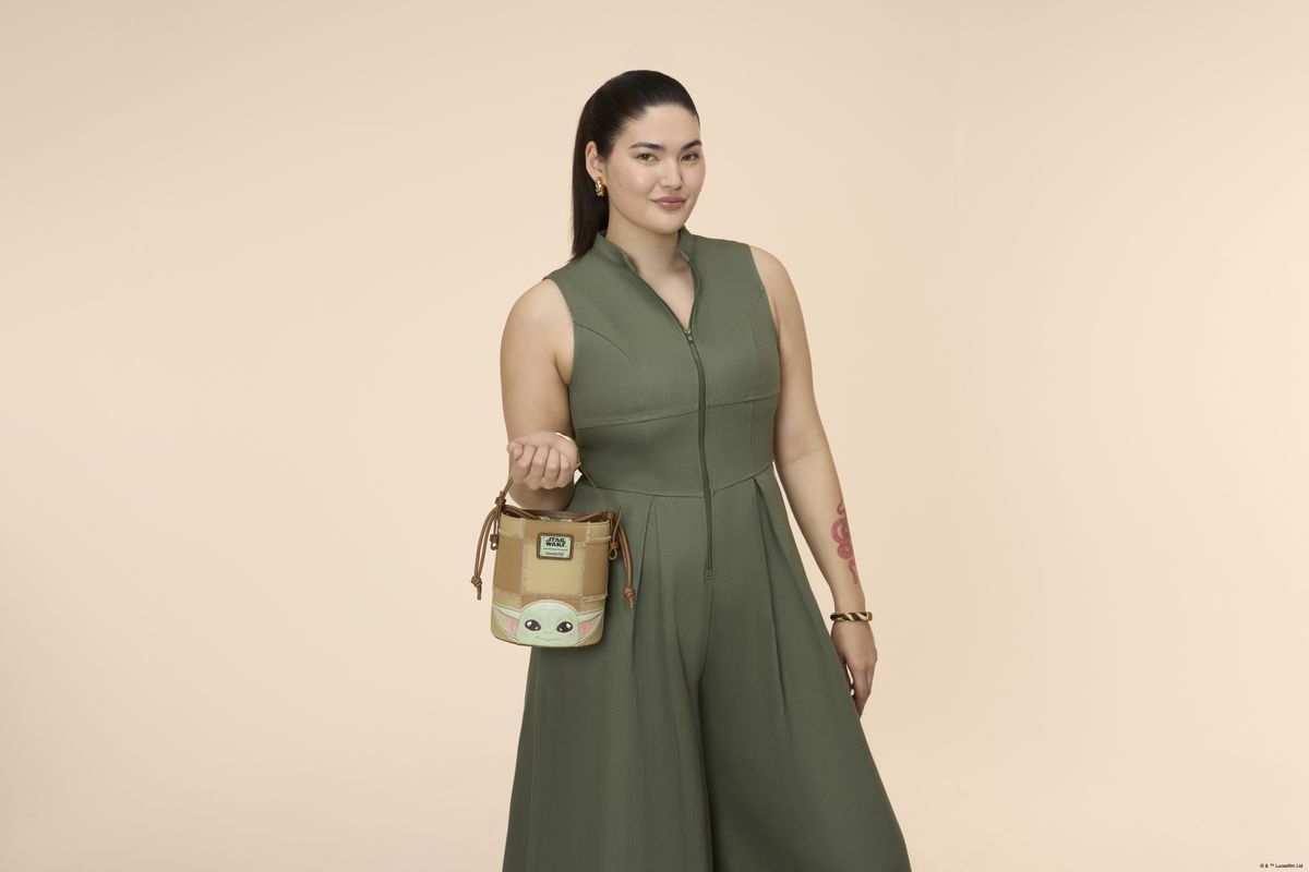 A woman holding a Loungefly bucket crossbody bag in a pink environment