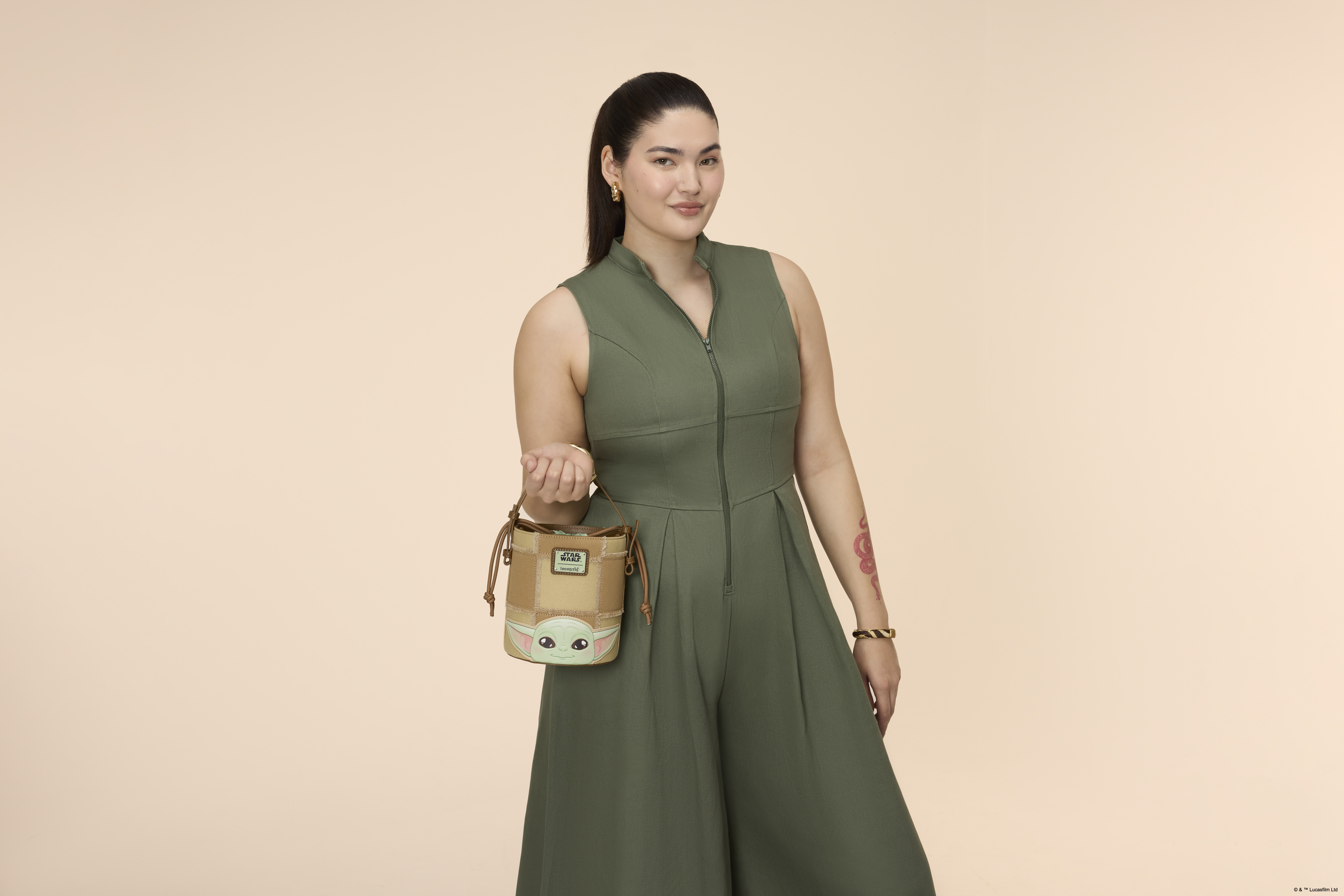 A woman holding a Loungefly bucket crossbody bag in a pink environment