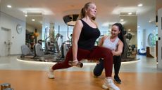 A woman trains in the gym with her female personal trainer