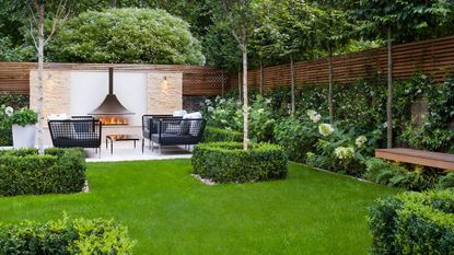outdoor fireplace and seating in a garden with evergreen planting