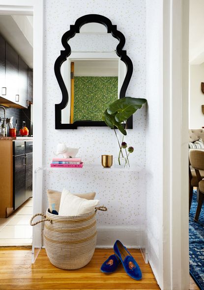 Delicately wallpapered hallway with contemporary mirror and floating shelf