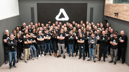 A group shot of the Affinity team in Affinity t-shirts, the large A logo behind them