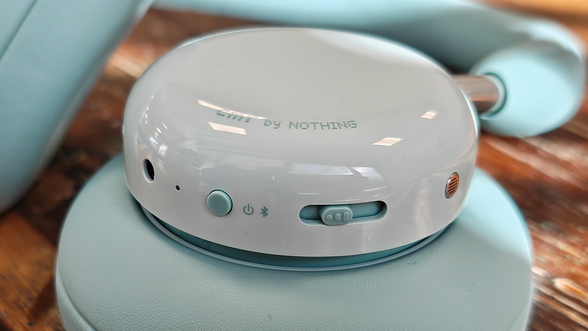 CMF Headphone Pro; a pair of light green headphones on a wooden table