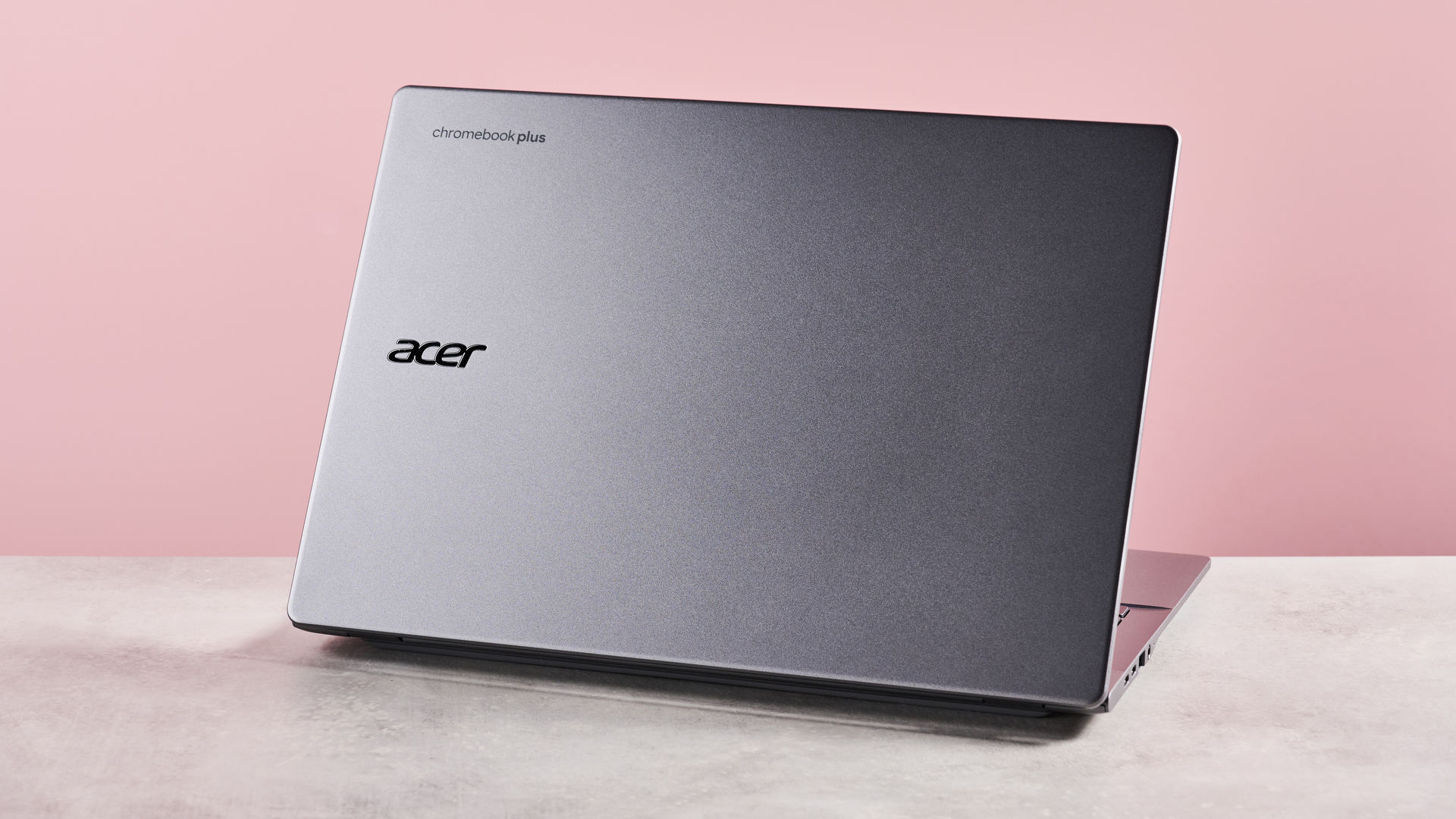 Back of Acer Chromebook Plus 514, on desk with pink background