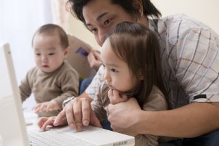 Asian father with two children at laptop computer