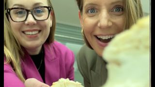 Two women hold up spongy white materials to the camera, one woman wears glasses and a pink blazer and the other has a gold hoop earring