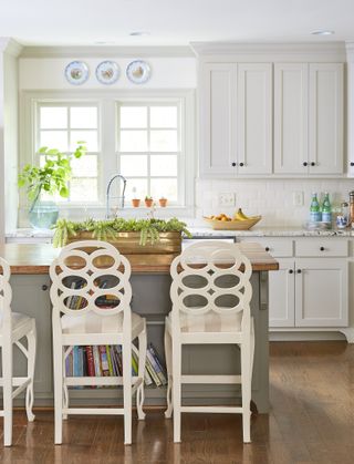 Kitchen with gray island and wood countertop, white cabinets and wood floor