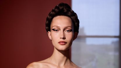 woman with an intricate braided updo, pink lipstick, and cat eye makeup