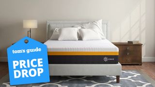 Image shows a Zinus cooling mattress on a white bedframe with a lamp to the left and a brown bureau to the right