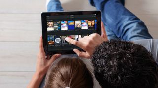 Two people are browsing movies and shows on Plex on a tablet