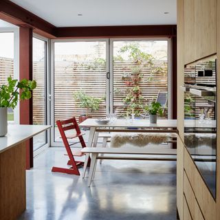 open plan kitchen diner with bifold doors and a dining table with a red Tripp Trapp high chair