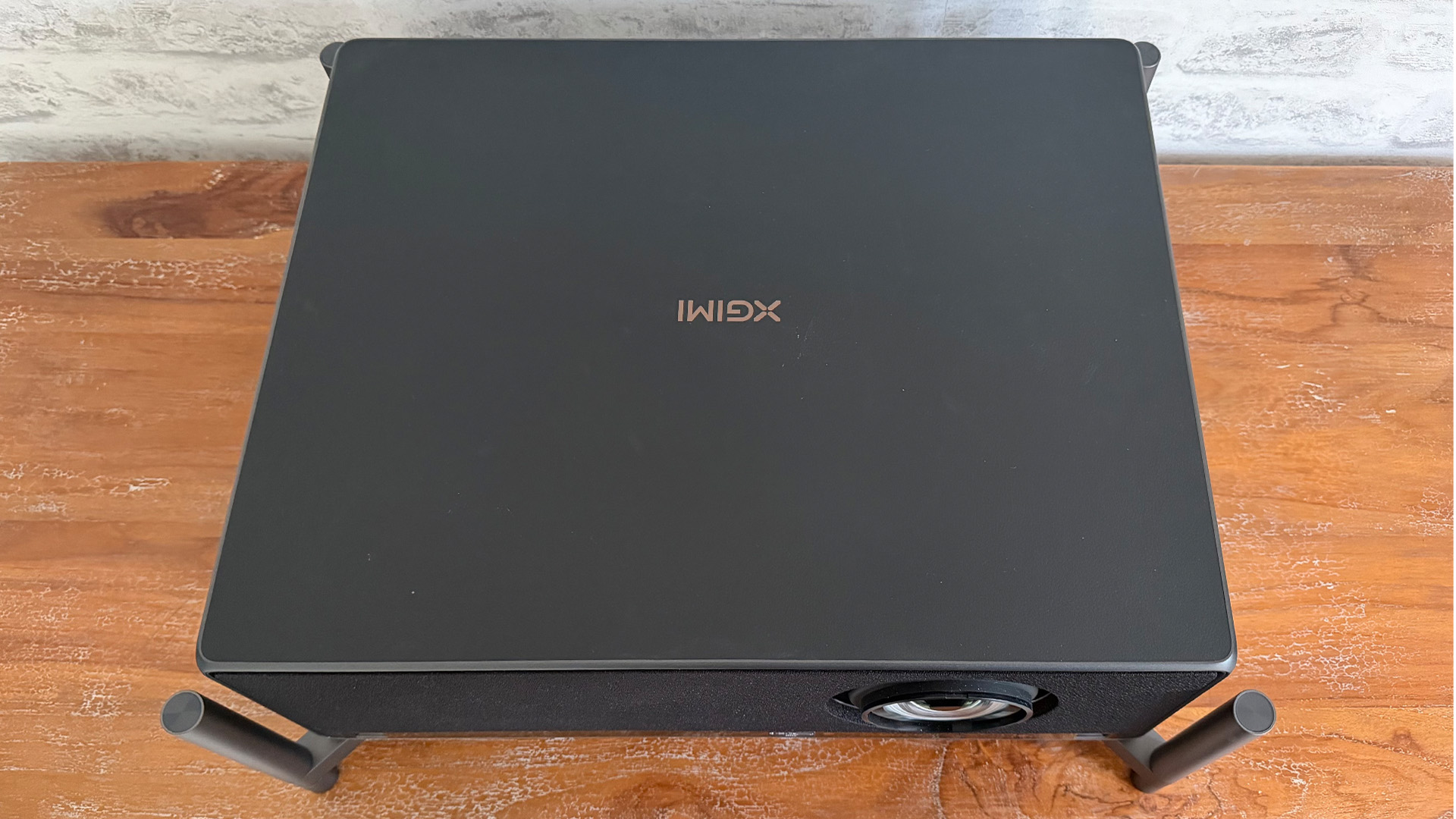 Xgimi Titan home cinema projector on wooden surface with legs attached top-down angle