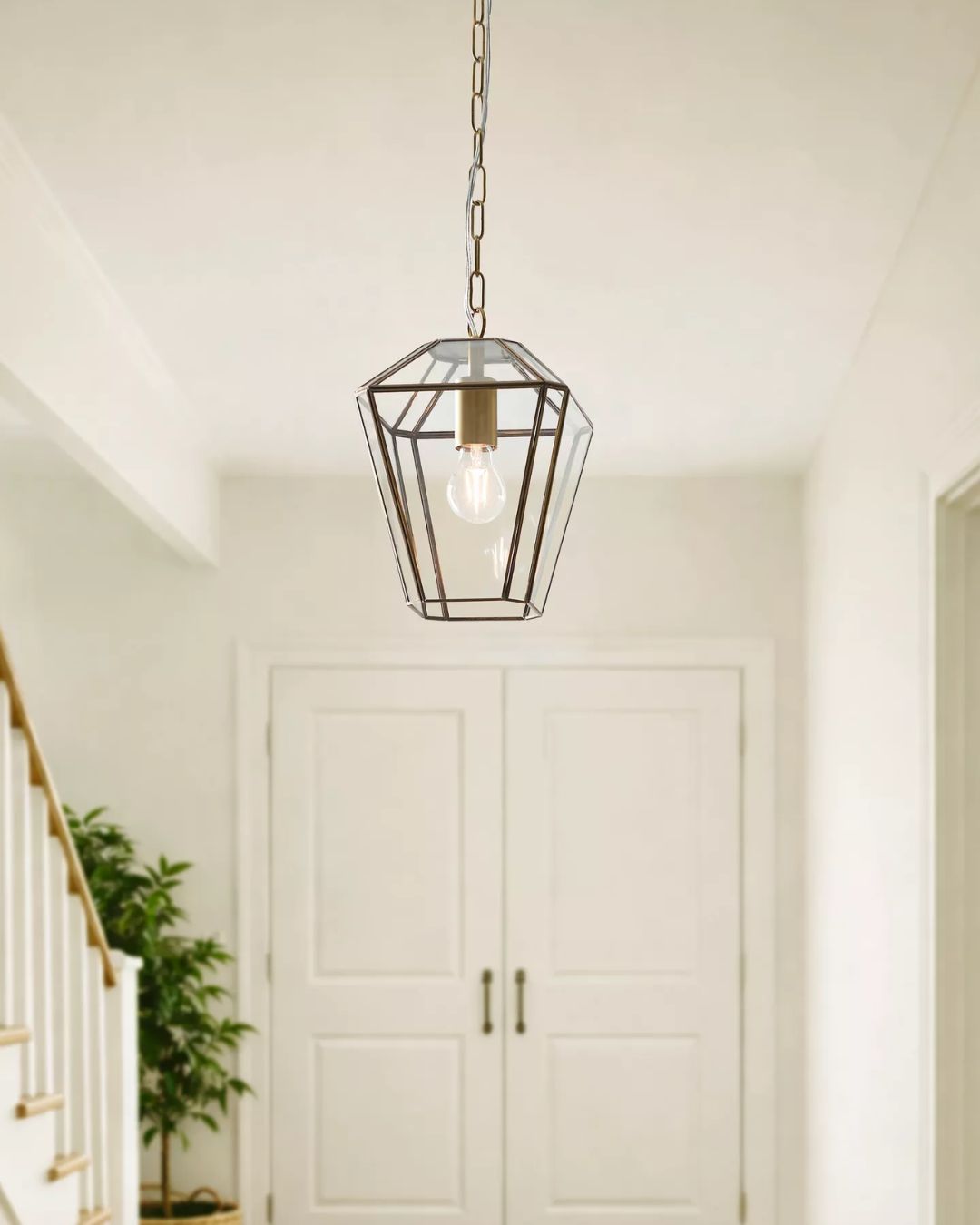 Timeless Glass Lantern Ceiling Light, Clear/Antique Brass, installed in a white-washed room with classical decor and plants.