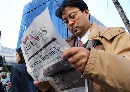 Man reads newspaper in Tokyo