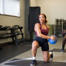 A woman working out with a medicine ball at a gym