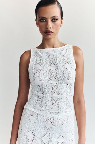 A model wears a sleeveless white lace top