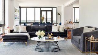 White living room with a black velvet sofa