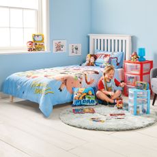 kids bedroom with light blue wall white bed with toy story bedding and girl is playing on floor