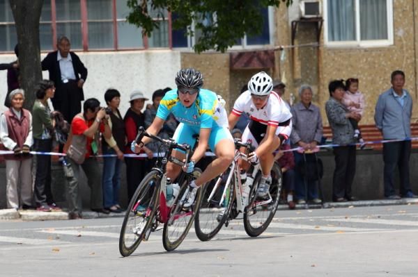 A Kazachstan rider takes a town corner ahead of Andrea Graus (Austria)