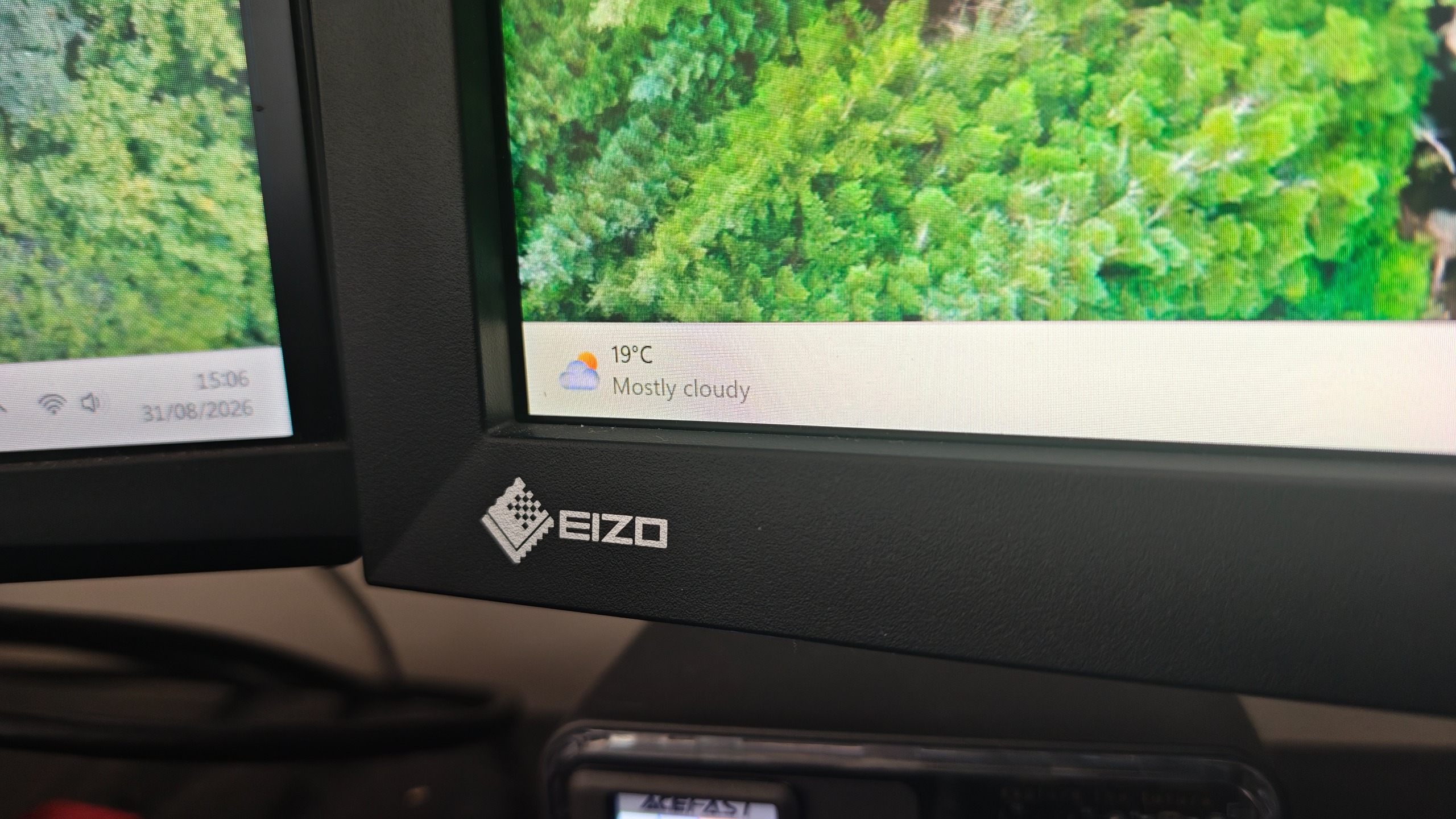An Eizo ColorEdge CG2700X monitor sitting on a desk, showing a forest image on its screen