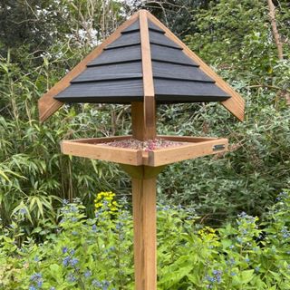 Wooden bird table with roof for shelter